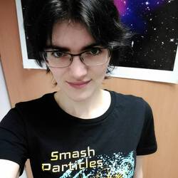 Close up headshot of me in front of an image of the Bullet Cluster, wearing a black shirt that says Smash Particles.